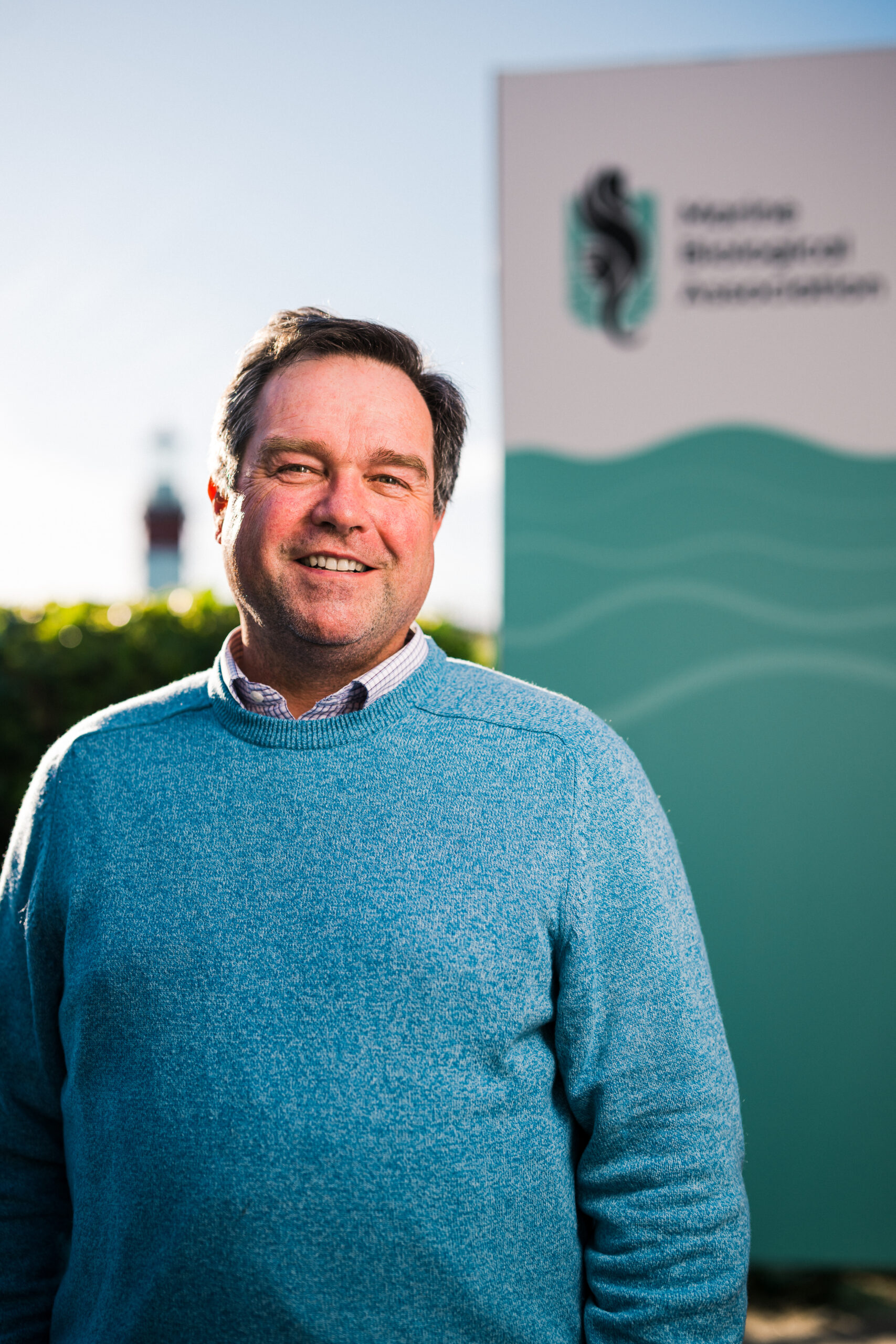 Director, Professor Willie Wilson smiling and standing in front of our MBA sign and Smeaton's lighthouse in the distance.