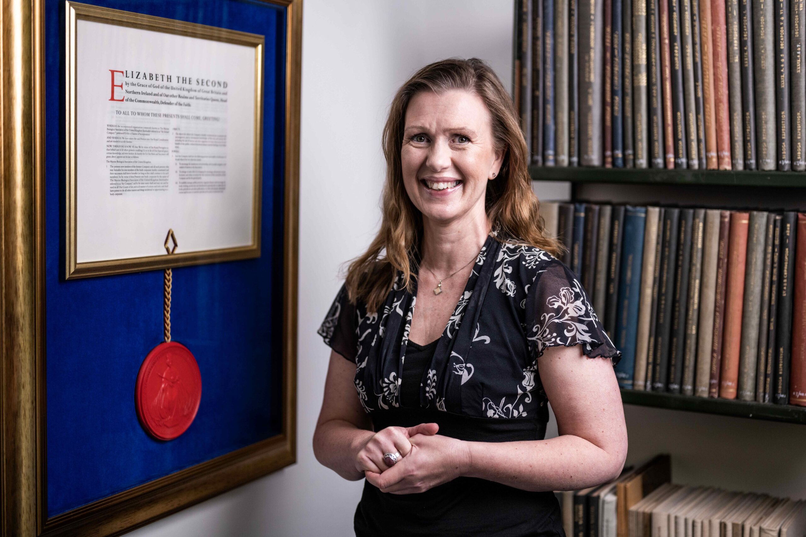 Alex Street smiling and standing in front of our Royal Charter award.