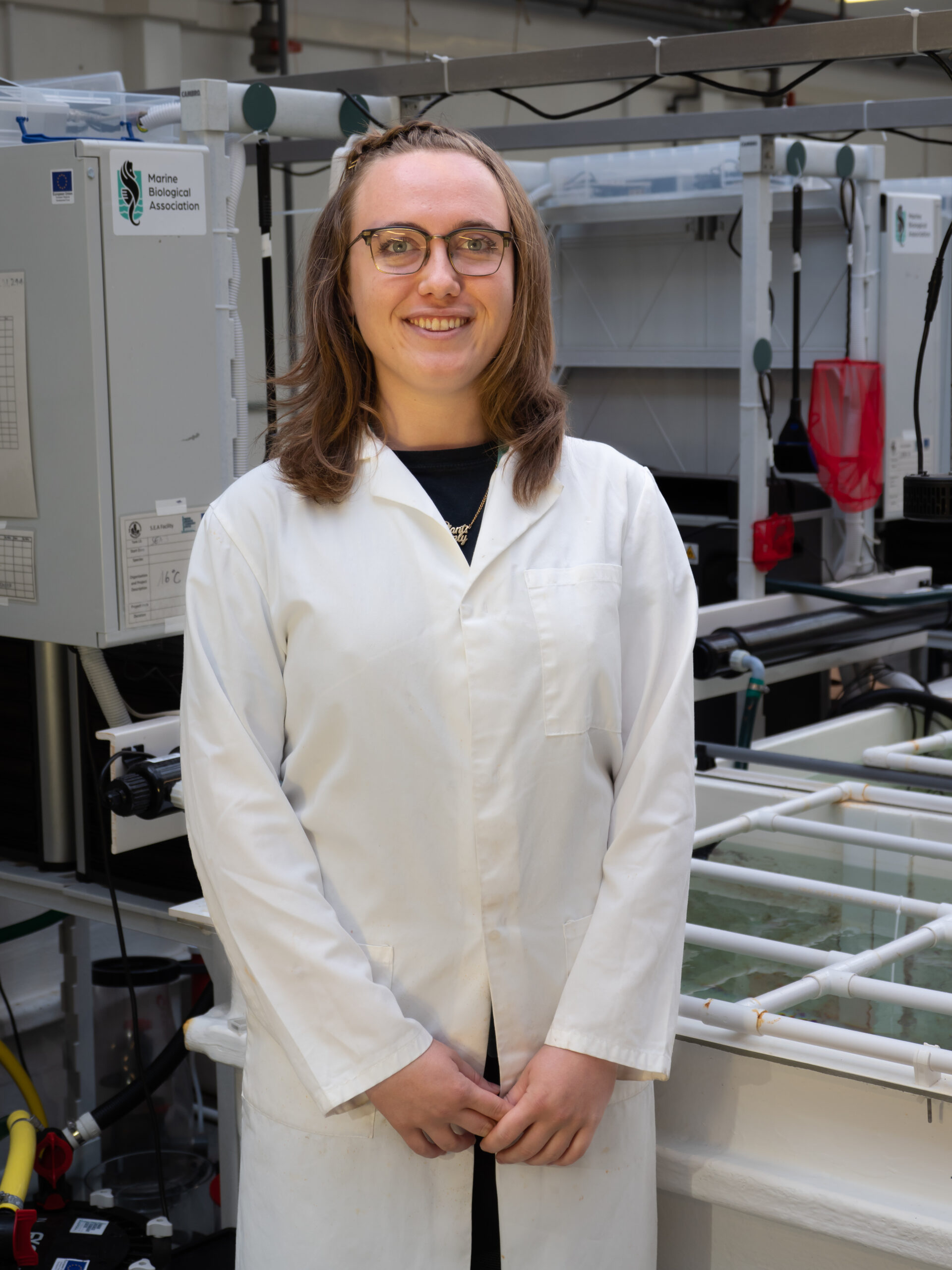 Profile photo staff member Belle Heaton standing in front of aquarium tanks