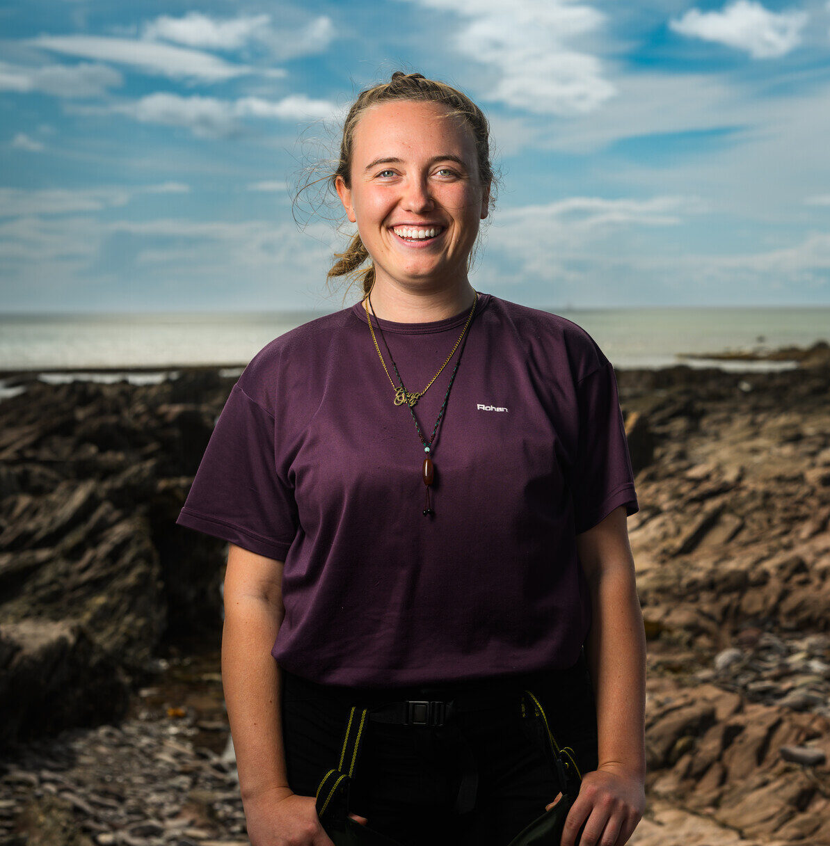 Belle Heaton smiling on the rocky shore