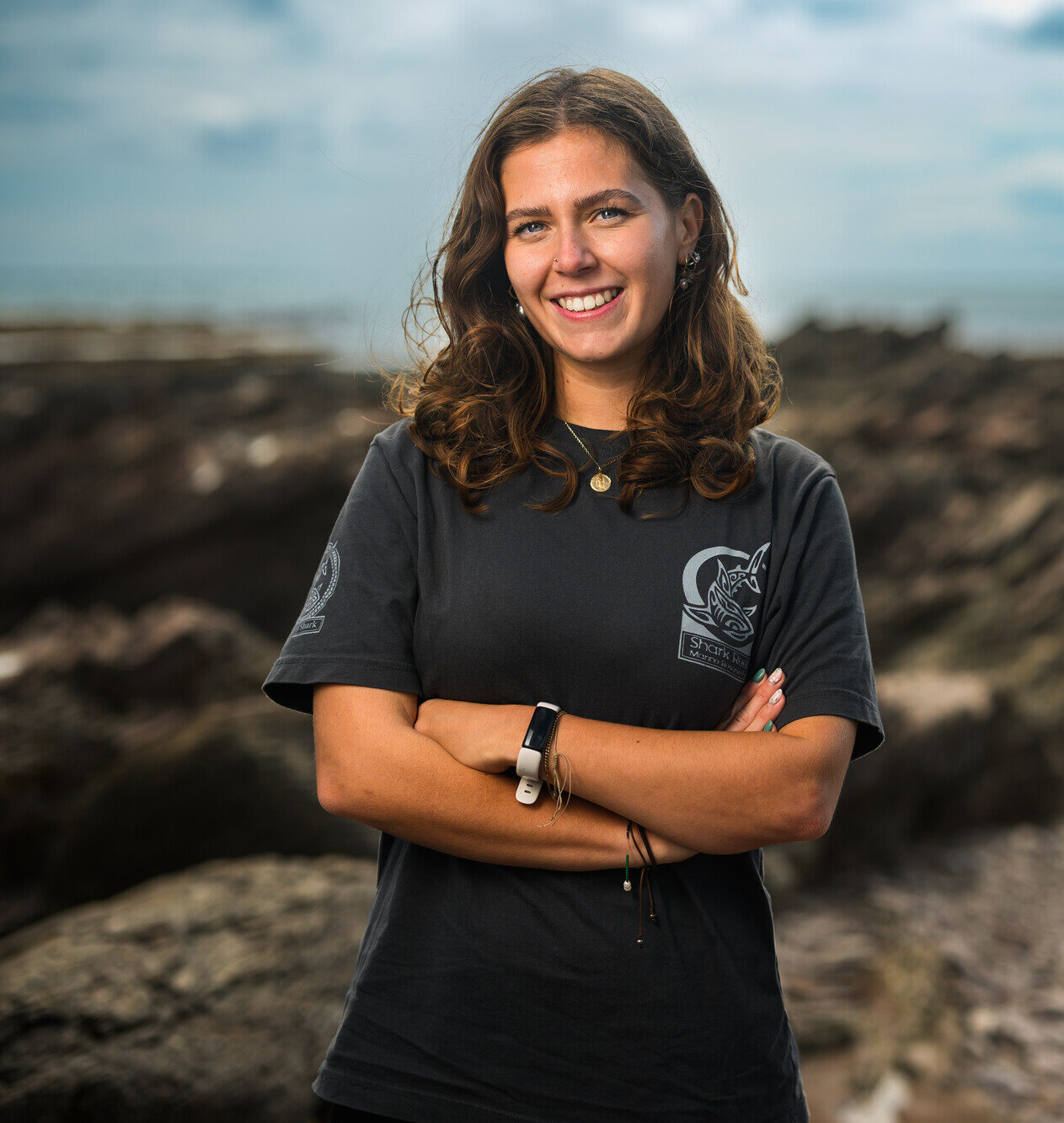 Tayla Leathers on the rocky shore, smiling.