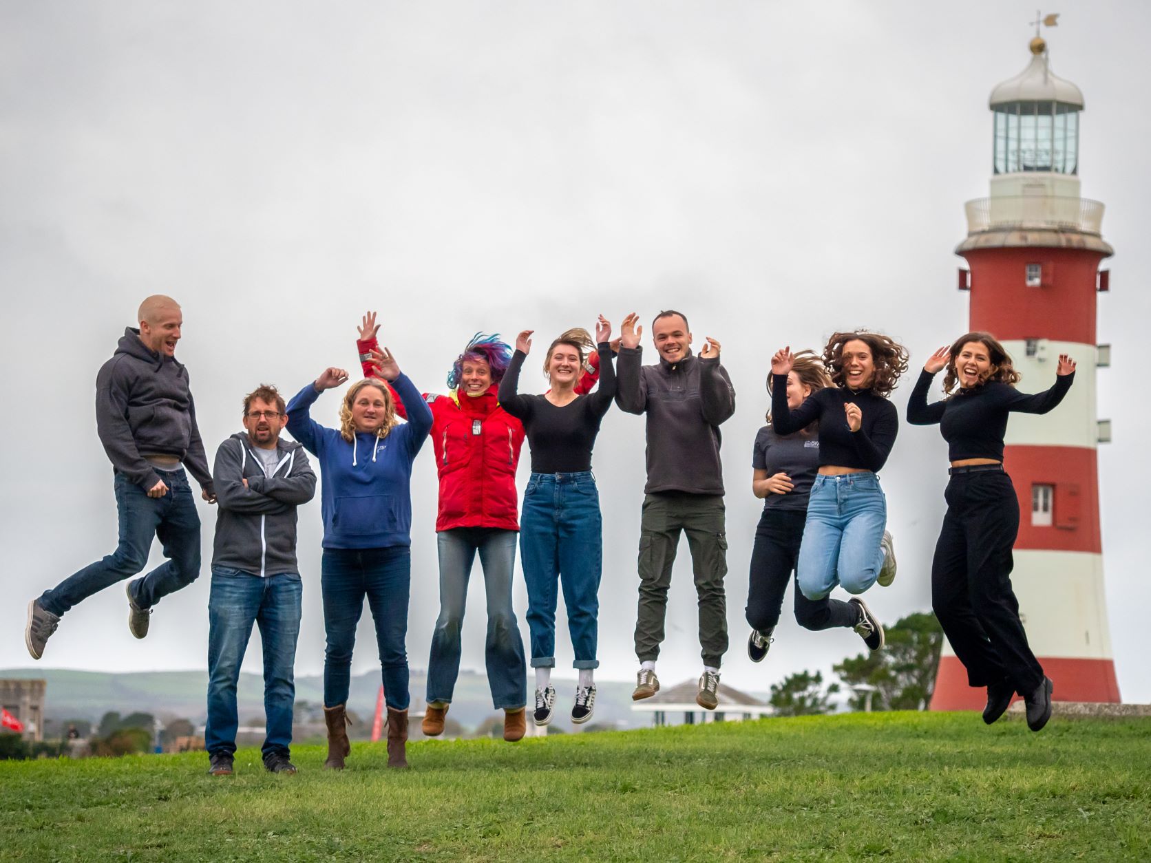 A group of scientists jump for joy in front of Smeaton's lighthouse, Plymouth