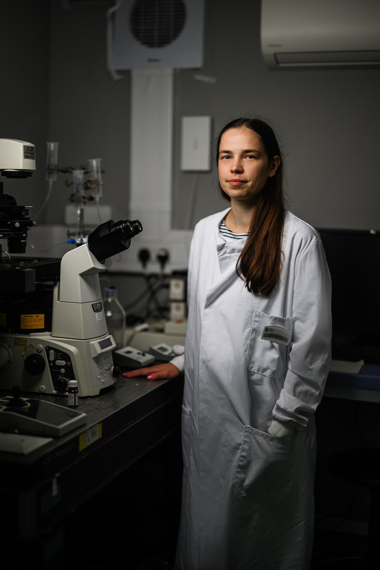 Dr Ellen Harrison standing beside microscope