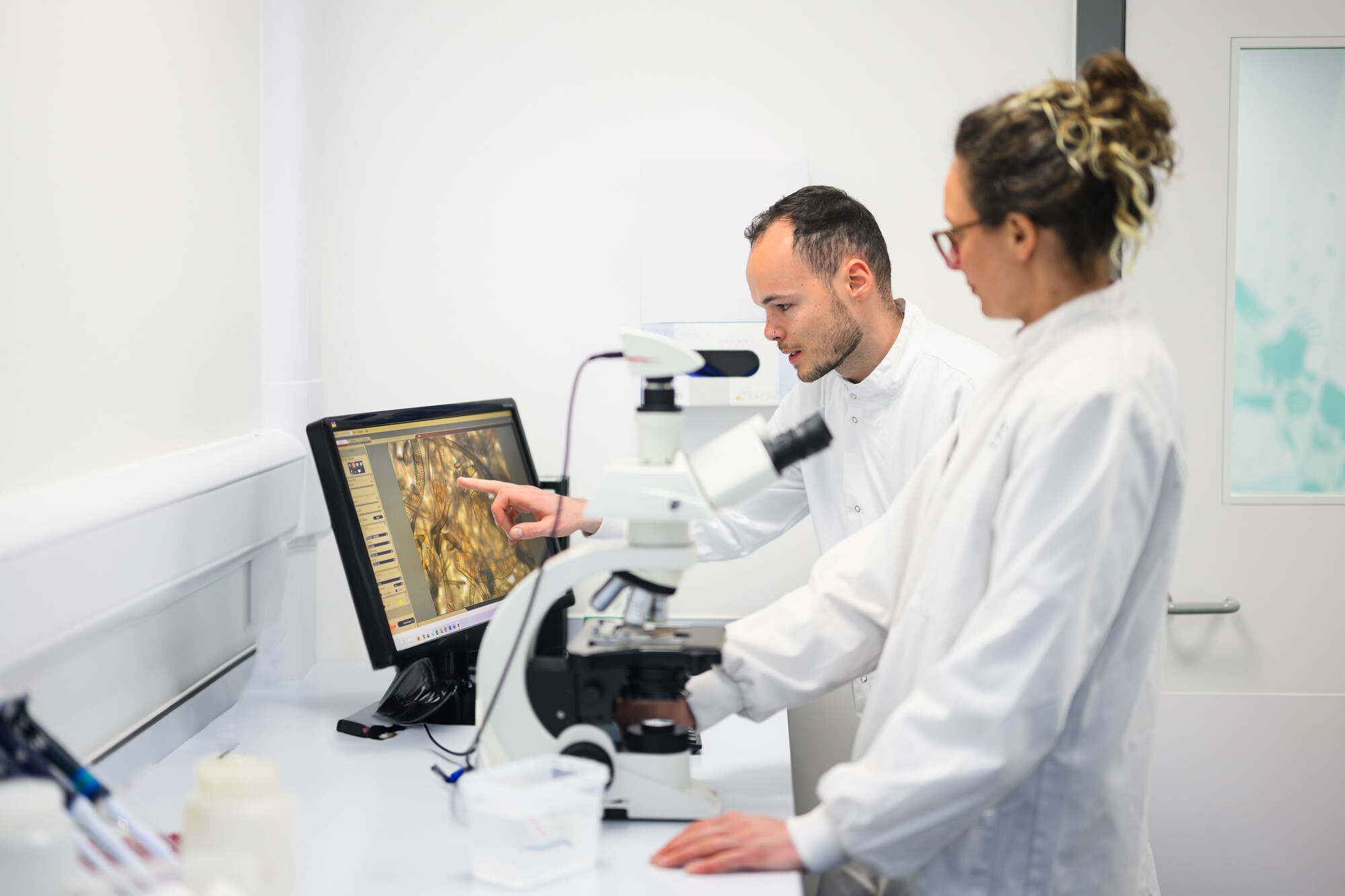 Researchers Cat Wilding and Fraser in white lab coats analysing kelp in the lab