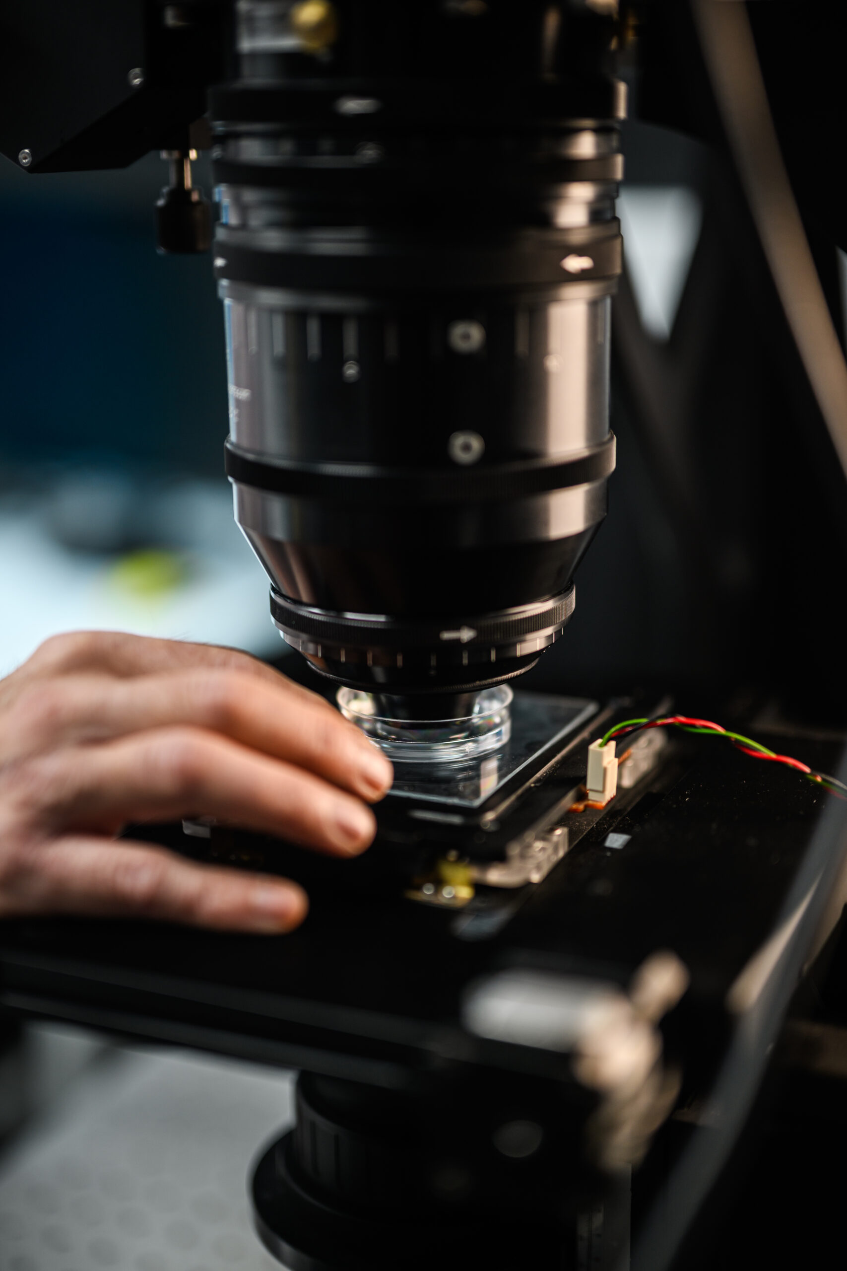 Large microscop close-up over glass dish, hand in view to the left side.