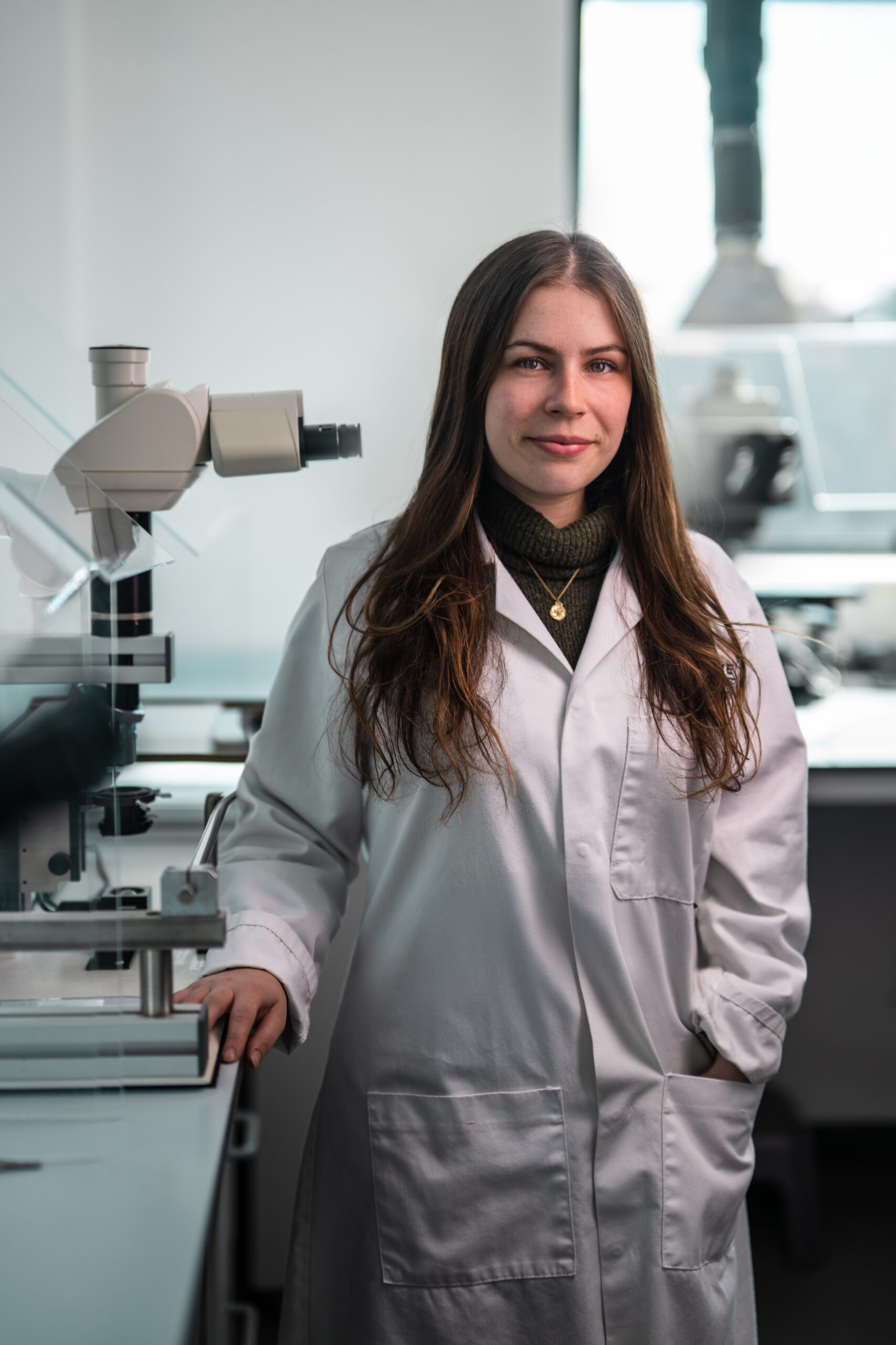 Katie Nash, young woman in lab coat with long brown hair.