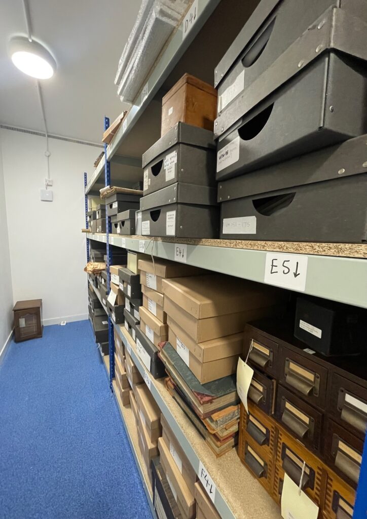 Rows of cardboard boxes on metal numbered shelves.