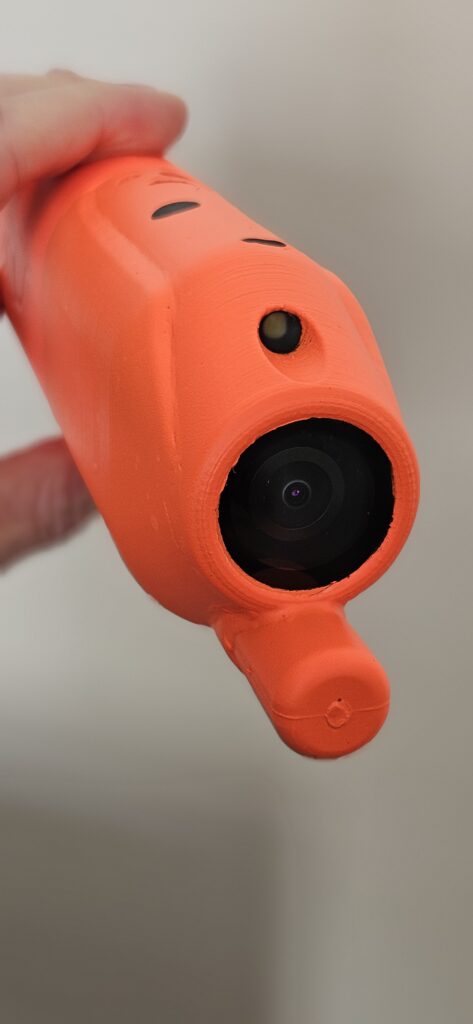 A camera tag for shark tagging - bright orange and black cylindrical object made of rubber