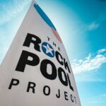 Vertical banner with the words The Rock Pool Project on it, with a sunny blue sky and little clouds behind.